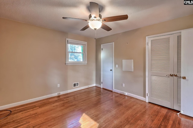 unfurnished bedroom featuring ceiling fan, hardwood / wood-style floors, and a textured ceiling