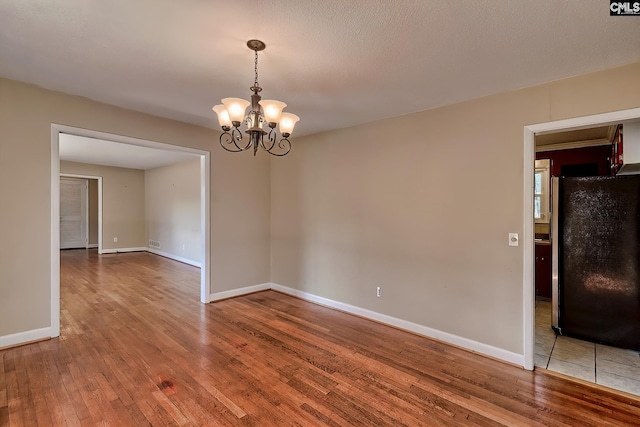 unfurnished room with hardwood / wood-style floors and an inviting chandelier