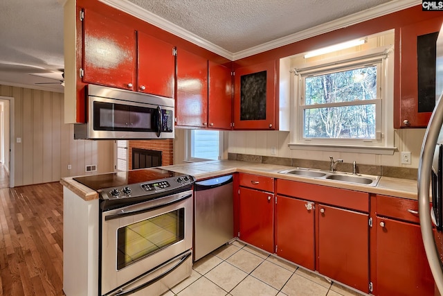 kitchen featuring appliances with stainless steel finishes, ornamental molding, a textured ceiling, ceiling fan, and sink