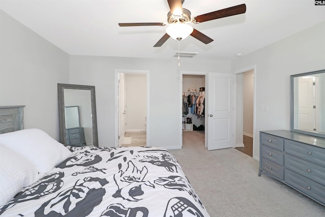 carpeted bedroom with ceiling fan, a spacious closet, ensuite bathroom, and a closet