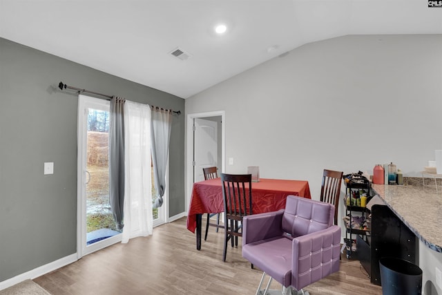 dining space with vaulted ceiling, wood finished floors, and visible vents