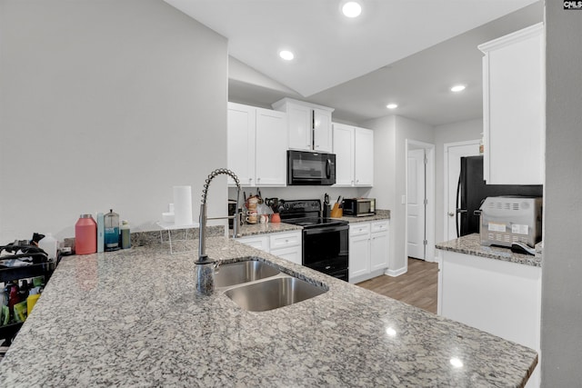 kitchen with black appliances, light stone counters, a sink, and white cabinets