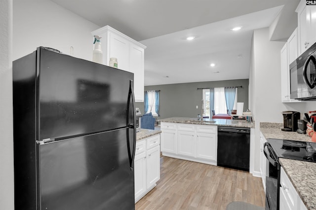 kitchen featuring white cabinets, black appliances, light stone counters, and light wood finished floors