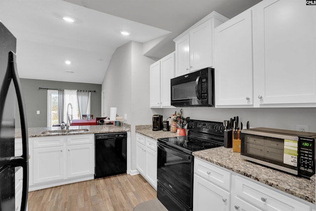 kitchen featuring a sink, light wood finished floors, black appliances, and light stone countertops