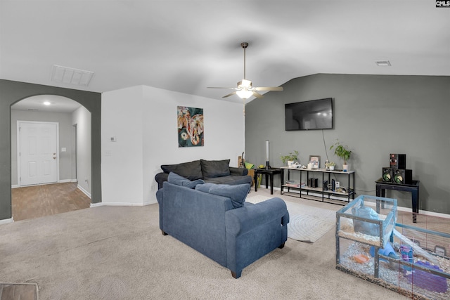 carpeted living room featuring baseboards, visible vents, arched walkways, a ceiling fan, and lofted ceiling