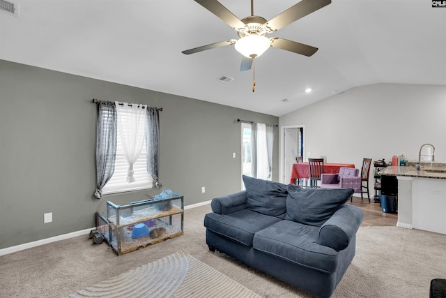 living area featuring light carpet, visible vents, baseboards, and vaulted ceiling