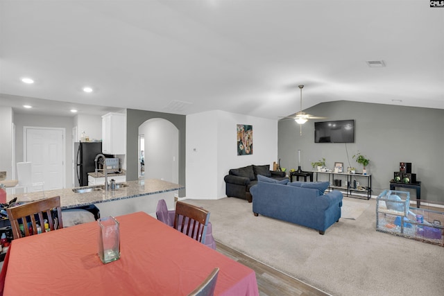 dining area with arched walkways, light carpet, visible vents, a ceiling fan, and vaulted ceiling