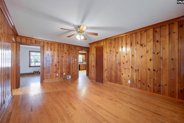 unfurnished room featuring light hardwood / wood-style floors, ceiling fan, a healthy amount of sunlight, and ornamental molding