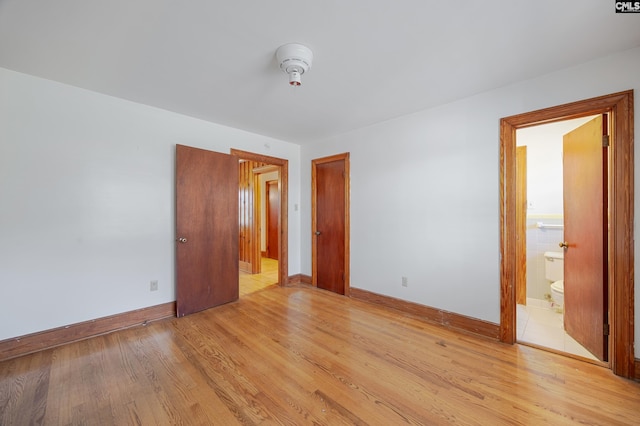 unfurnished bedroom with ensuite bathroom and light wood-type flooring