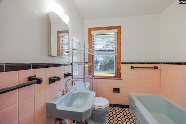 bathroom with toilet, tile walls, a bathing tub, and sink