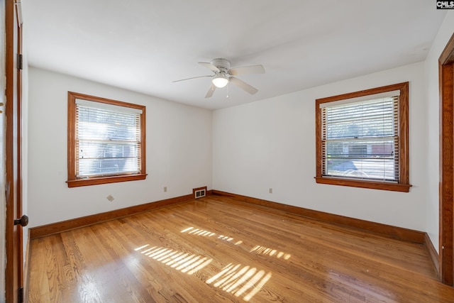 spare room featuring ceiling fan, a healthy amount of sunlight, and light hardwood / wood-style flooring