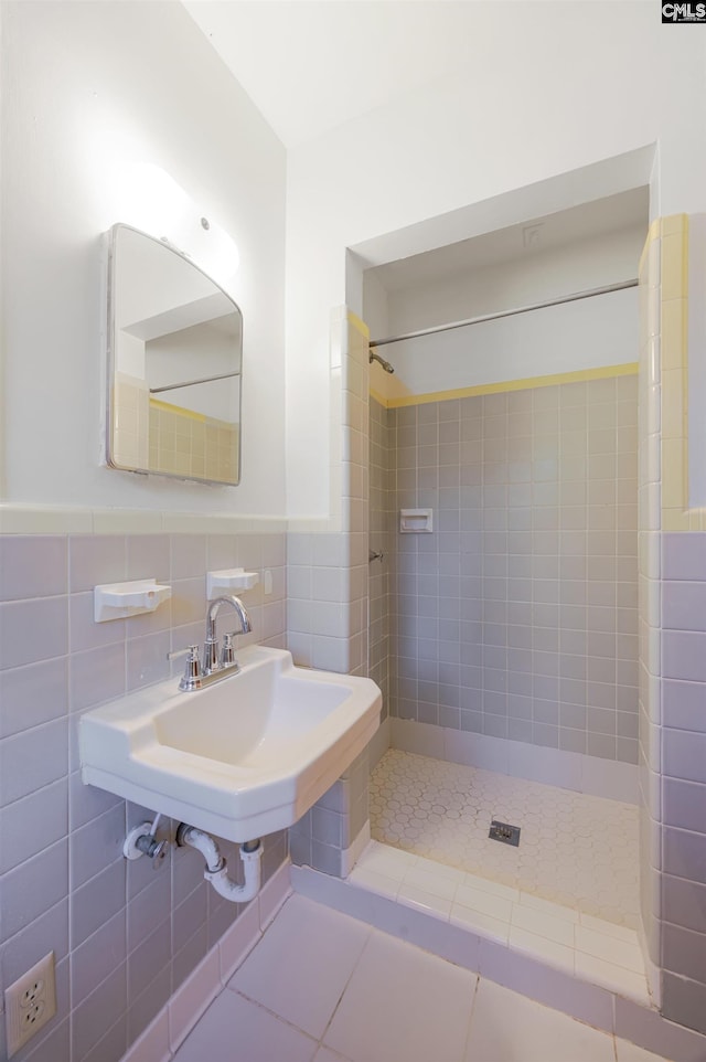 bathroom featuring tiled shower, tile patterned flooring, tile walls, and sink