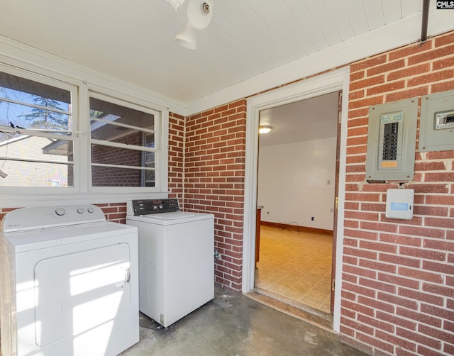 laundry room featuring brick wall and washing machine and clothes dryer