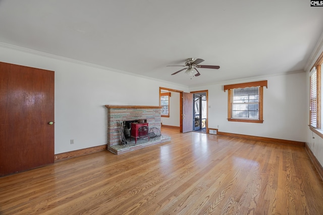 unfurnished living room with a wood stove, crown molding, ceiling fan, and light hardwood / wood-style floors