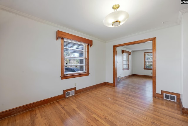 empty room featuring light wood-type flooring and crown molding