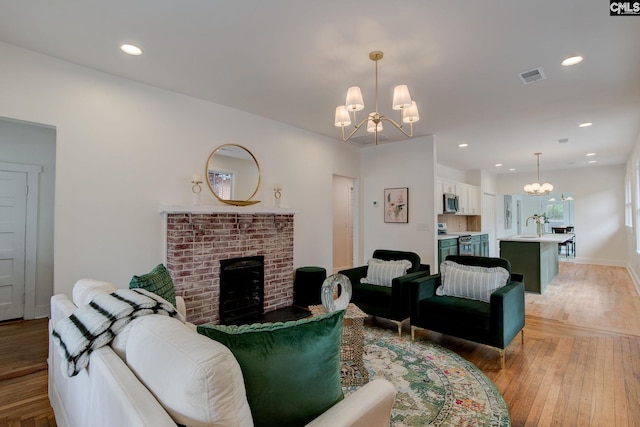 living room featuring a fireplace, light hardwood / wood-style flooring, a notable chandelier, and sink