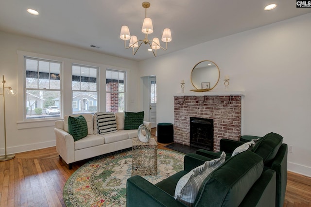 living room featuring hardwood / wood-style floors, a fireplace, and a chandelier