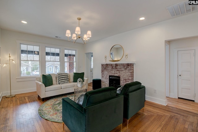 living room featuring wood-type flooring, a fireplace, and a chandelier