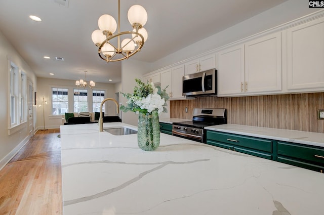 kitchen with pendant lighting, an inviting chandelier, sink, appliances with stainless steel finishes, and white cabinetry