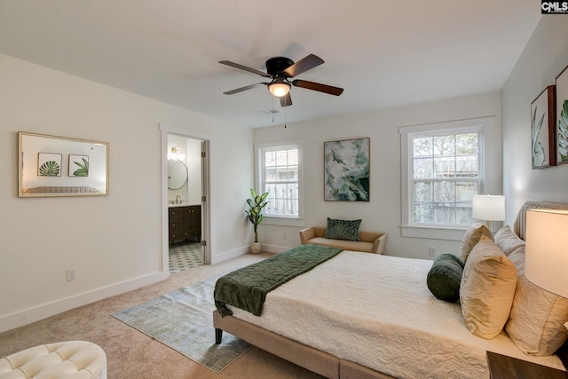 carpeted bedroom featuring multiple windows, ensuite bath, and ceiling fan