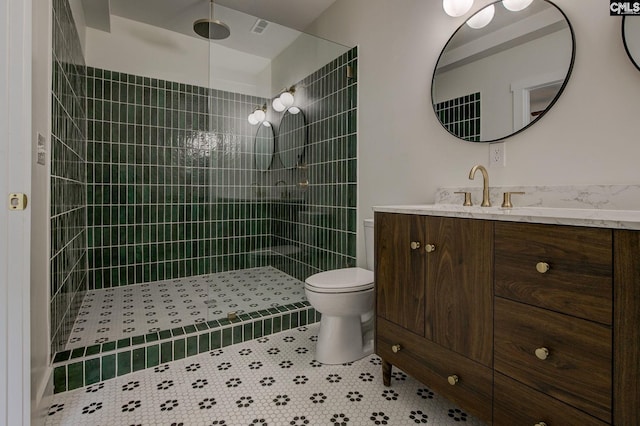 bathroom with tiled shower, vanity, tile patterned floors, and toilet