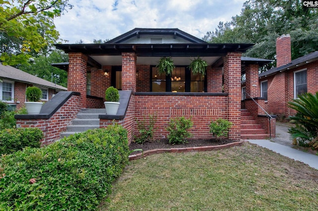 bungalow-style home featuring a front yard and covered porch