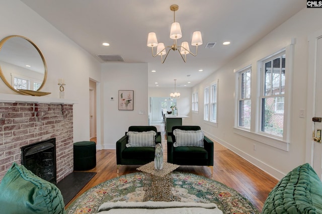 living room with a fireplace, hardwood / wood-style floors, and a notable chandelier