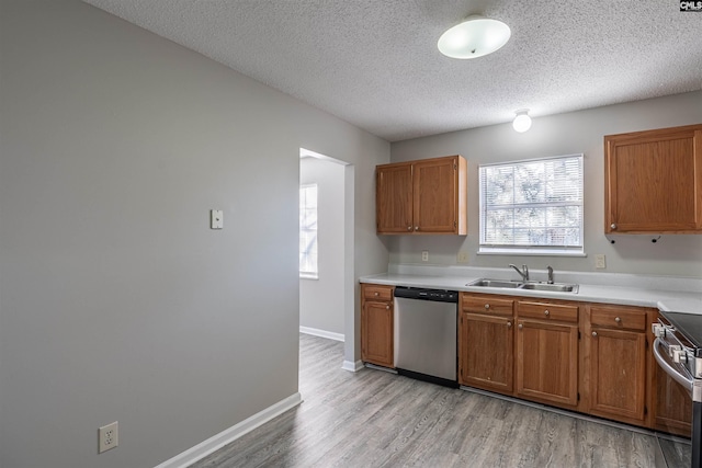 kitchen featuring a textured ceiling, stainless steel appliances, light hardwood / wood-style floors, and sink