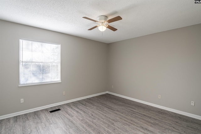 empty room with a textured ceiling, ceiling fan, and dark hardwood / wood-style floors