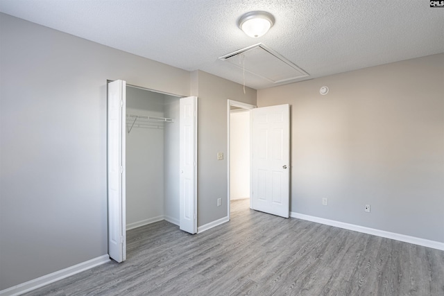 unfurnished bedroom with a textured ceiling, light hardwood / wood-style flooring, and a closet