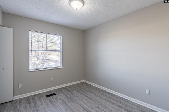 spare room featuring wood-type flooring and a textured ceiling