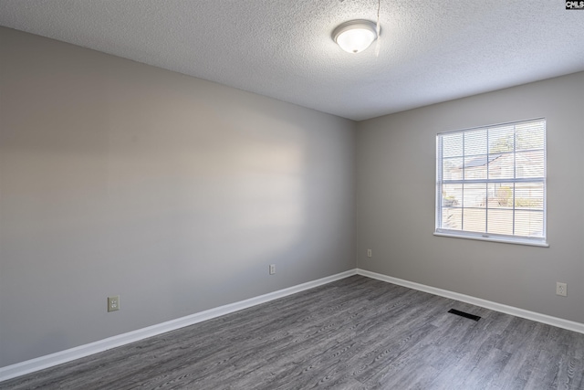 empty room featuring dark hardwood / wood-style flooring and a textured ceiling