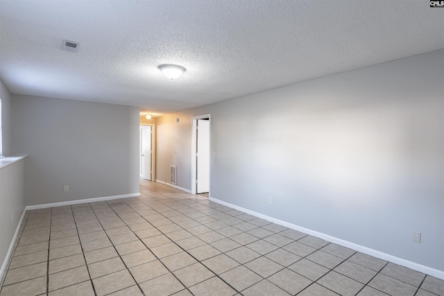 spare room featuring light tile patterned flooring and a textured ceiling