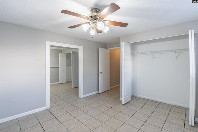 unfurnished bedroom with ceiling fan, light tile patterned flooring, a textured ceiling, and a closet