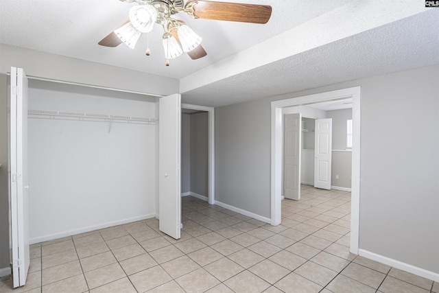 unfurnished bedroom featuring ceiling fan, a closet, light tile patterned floors, and a textured ceiling