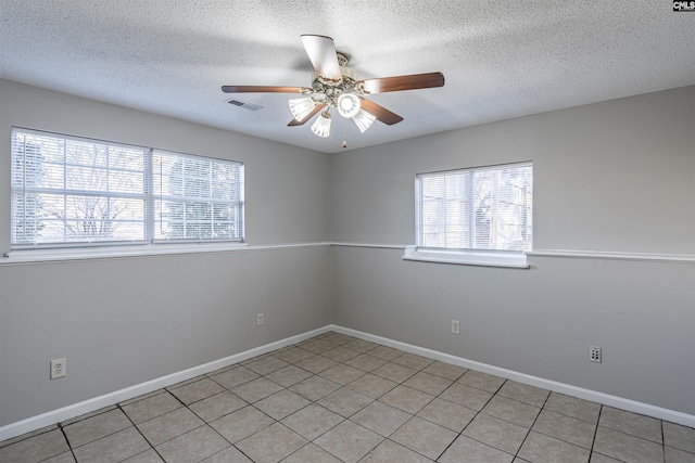 tiled spare room with a textured ceiling and ceiling fan