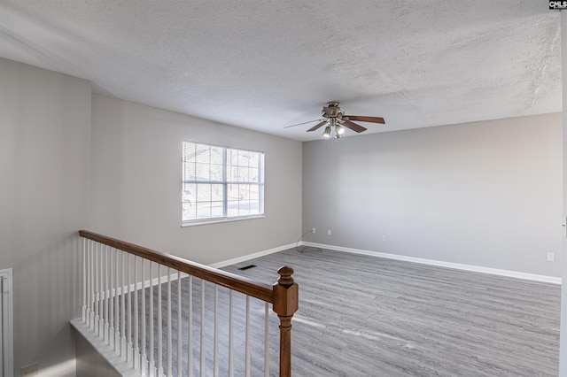 stairs with hardwood / wood-style floors, a textured ceiling, and ceiling fan