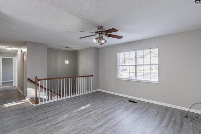 spare room with hardwood / wood-style flooring, ceiling fan, and a textured ceiling