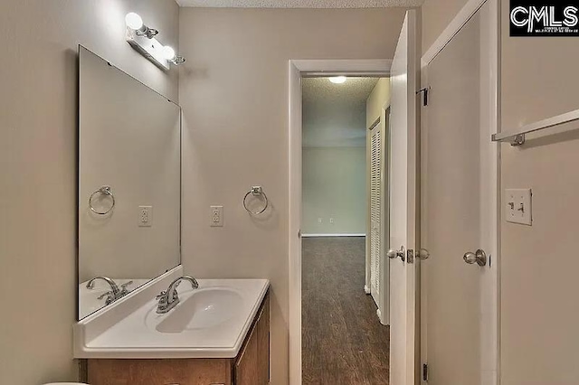 bathroom with hardwood / wood-style flooring, vanity, and a textured ceiling