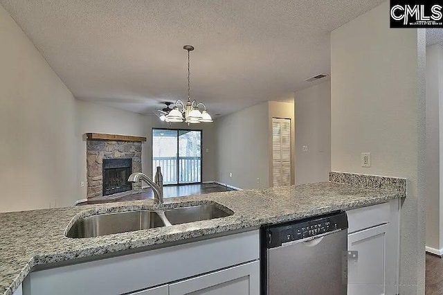 kitchen featuring an inviting chandelier, sink, stainless steel dishwasher, a textured ceiling, and light stone counters