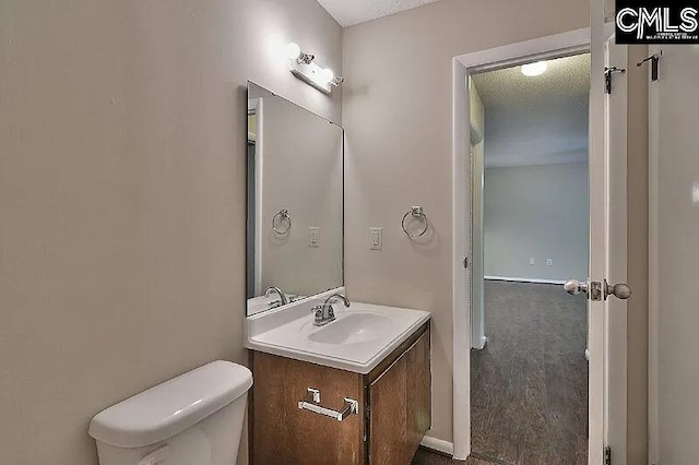 bathroom with vanity, toilet, and a textured ceiling