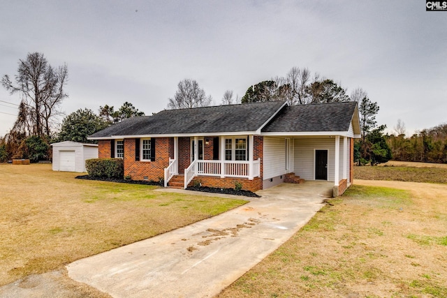 single story home featuring a garage, covered porch, an outbuilding, and a front lawn