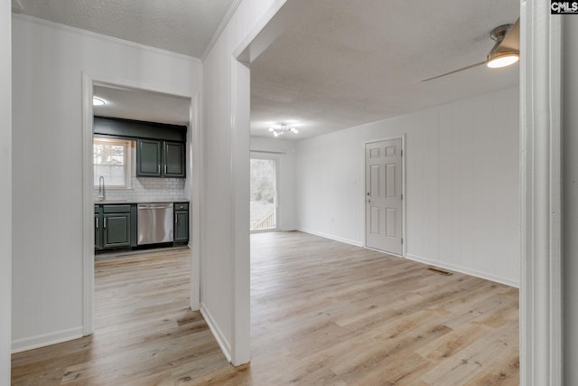 hallway with plenty of natural light, crown molding, light hardwood / wood-style flooring, and a textured ceiling