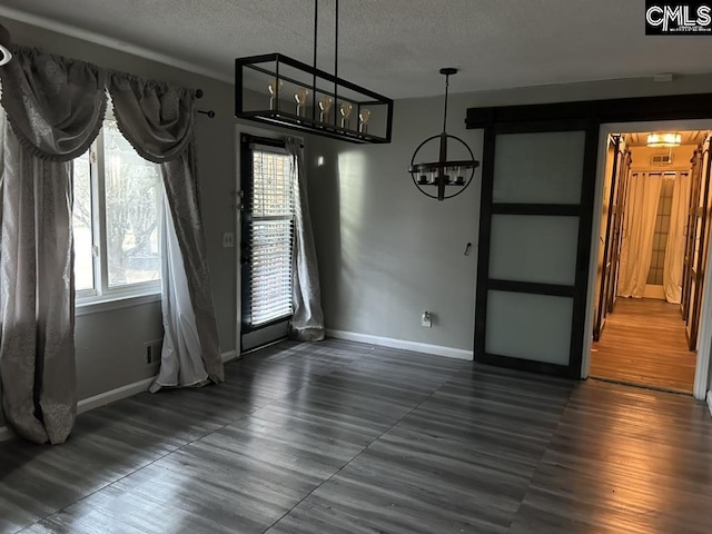 unfurnished dining area with dark wood-type flooring, a notable chandelier, and a textured ceiling