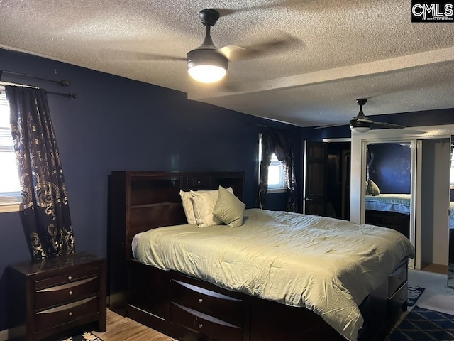 bedroom with ceiling fan, a textured ceiling, and light hardwood / wood-style flooring