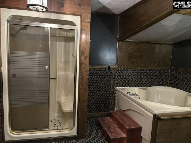 bathroom with tile patterned floors, independent shower and bath, tile walls, and a textured ceiling