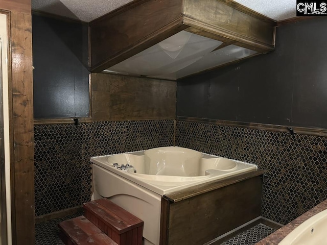 bathroom with tile walls, tile patterned flooring, a bathtub, and a textured ceiling