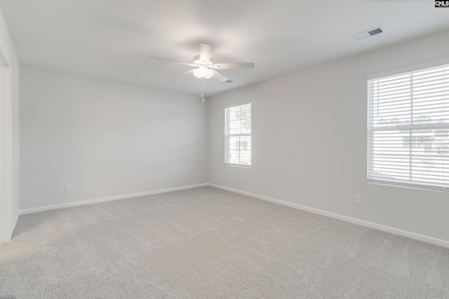 carpeted spare room with ceiling fan and plenty of natural light