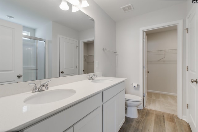 bathroom with vanity, hardwood / wood-style flooring, toilet, and a shower with door