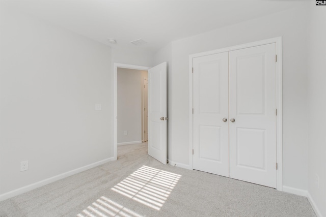 unfurnished bedroom with a closet and light colored carpet